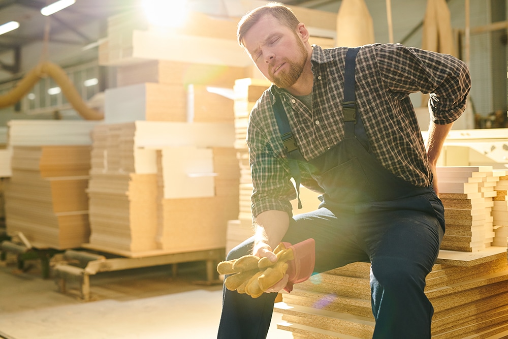 worker sitting down holding back in pain