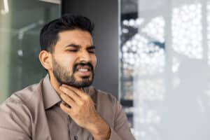 man holding his throat in pain