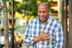 African American man clutching his chest in pain, suggesting possible chest discomfort.