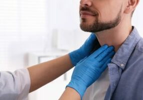 man getting his thyroid check by an emergency room nurse